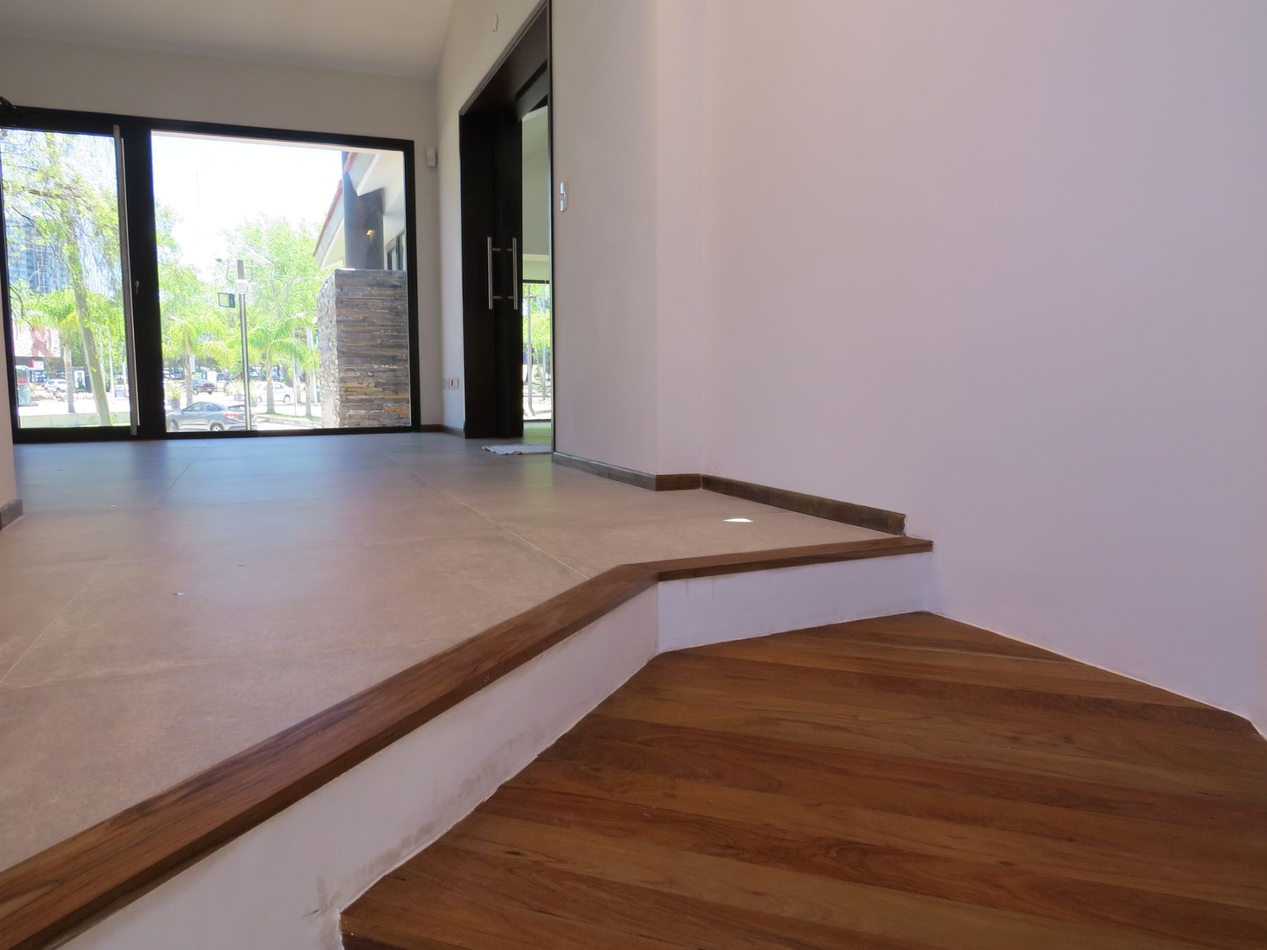 Es una fotografía tomada desde la escalera, en la misma se puede ver el desembarco de la escalera, el piso de la planta alta que está revestido en porcelanato, con sus zócalos de madera.